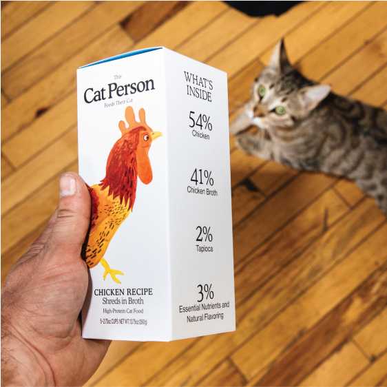 Cat looking up at Chicken Shreds wet food sleeve